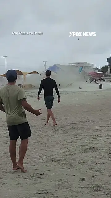Beachgoers scramble for cover as a waterspout suddenly moves ashore at Folly Bea