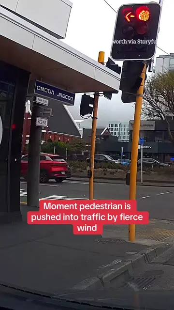 This is the moment a person was facing a fierce wind pushing them into oncoming 