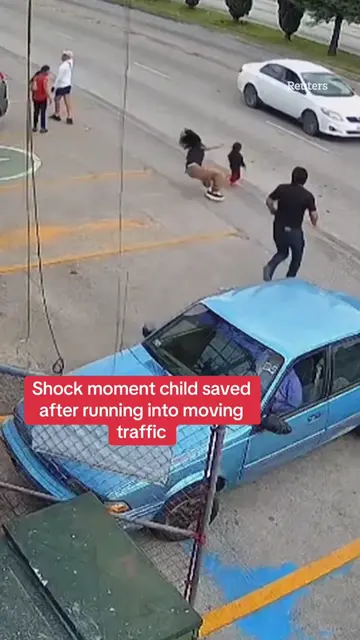 This is the shocking moment a child was saved after running into moving traffic.