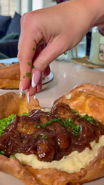 Giant Yorkshire pudding stuffed with cheddar chive mash, peas, and sausages in a
